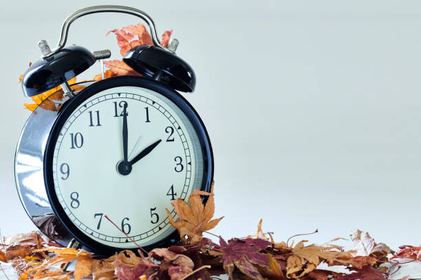 Image+of+autumn+Time+Change%2C+Fall+back+concept%2C+Dry+leaves+and+vintage+alarm+Black+Clock+on+wooden+table+outdoors+at+afternoon%2Cfor+text
